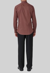 Langsleeve, bordeaux shirt in een strak ontwerp, met een gebogen zoom en knopenmanchetten, gecombineerd met zwarte broeken en schoenen.