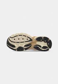 Η σόλα του αθλητικού παπουτσιού διαθέτει υφή με πολυδιάστατο σχέδιο, σε μπεζ βάση, με μαύρες καουτσούκ λεπτομέρειες και αξιοσημείωτες αυλακώσεις για πρόσφυση.