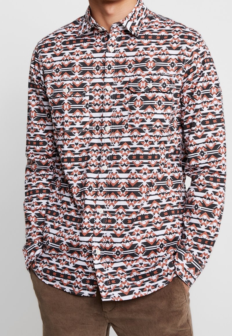 Lang shirt met lange mouwen en geometrische patronen in zwart, wit en roestkleuren, gemaakt van lichtgewicht stof met een knoopsluiting aan de voorkant.