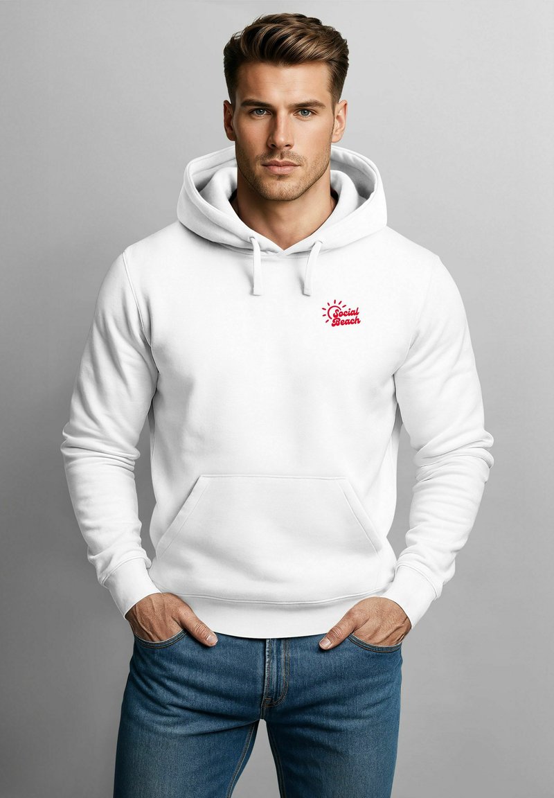 Weißer Hoodie mit einer Fronttasche, ausgestattet mit einem kleinen roten "Social Beach"-Logo. Das Material ist glatt und hat eine Kordelzugkapuze. Lässige blaue Jeans.