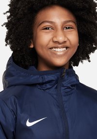 Marineblaues Kapuzenjacke mit glatter Textur, ausgestattet mit einem Frontreißverschluss und einem weißen Nike-Logo auf der linken Brust.