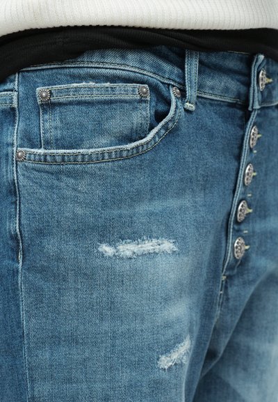 Jasnoniebieskie dżinsy z wykończeniem w stylu distressed, z zapięciem na guziki ozdobnymi metalowymi guzikami oraz z kieszeniami z przodu.