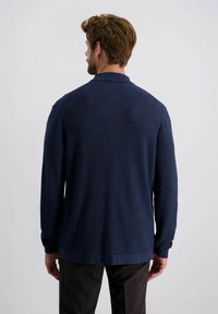 Marineblauer, langärmliger Cardigan mit strukturiertem Strickmuster, klassischem Kragen und geradem Saum. Der Stoff scheint weich und warm zu sein.