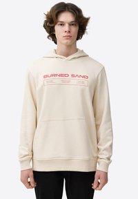 Sudadera beige con un bolsillo frontal tipo canguro, capucha ajustable con cordón y texto en rojo "BURNED SAND" en el pecho.