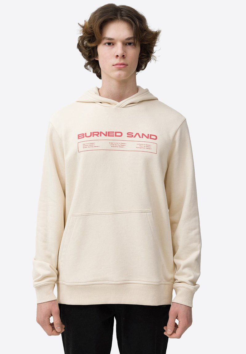 Sudadera beige con un bolsillo frontal tipo canguro, capucha ajustable con cordón y texto en rojo "BURNED SAND" en el pecho.