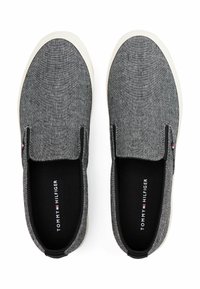Scarpe slip-on con tomaia in tessuto grigio scuro, suola in gomma bianca, interno nero e dettagli del logo. Presentano un design minimalista.