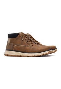 Botas de cuero marrón hasta el tobillo con un cuello acolchado negro, puntera redonda, seis ojales con cordones y una suela de goma de color claro.