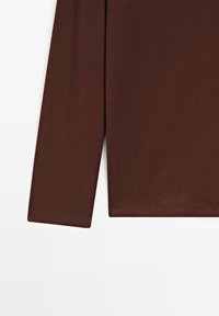 Brązowa koszula z długim rękawem o gładkiej fakturze, z dopasowanym krojem i prostym wykończeniem na krawędziach. Nadaje się do noszenia na co dzień.