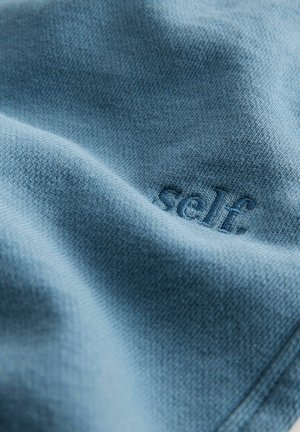 Plavi pleteni materijal s reljefnim detaljem "self. ", koji prikazuje mekanu teksturu i suptilan uzorak.
