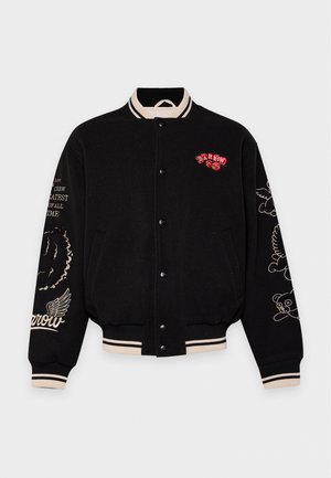 Veste universitaire noire avec col, poignets et ourlet à rayures crème, boutons-pression noirs et motifs brodés sur la poitrine et les manches.