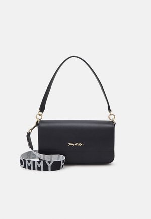 Borsa a spalla rettangolare nera in pelle con logo dorato e tracolla larga in tessuto rimovibile stampata con "Tommy Hilfiger" in bianco e nero.
