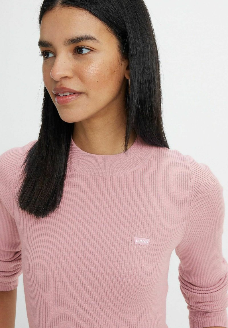 Maglione a coste rosa chiaro con scollo rotondo e maniche a tre quarti. Presenta un piccolo logo Levi's bianco sul petto.