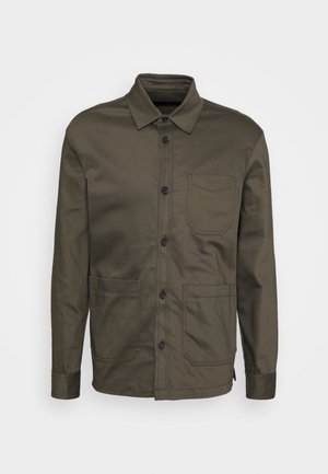 Veste boutonnée vert olive à manches longues avec col, trois poches avant et boutons noirs, présentée sur un fond uni.