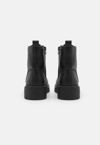 Bottines en cuir noir à talon avec une texture lisse, dotées d'une semelle en caoutchouc épaisse et de fermetures éclair sur les côtés pour un enfilage facile.