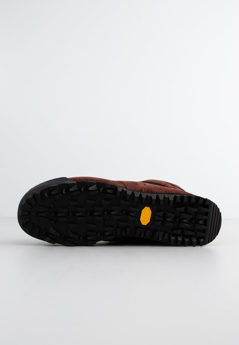 Semelle de chaussure de randonnée en daim marron avec un profond motif de traction en caoutchouc noir et le logo Vibram. Présente une finition texturée pour l'adhérence et la durabilité.