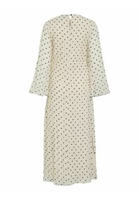 Lang kremhvit kjole med svarte polkadotter, med V-åpen rygg, vide ermer og teksturert stoff for ekstra visuell interesse.
