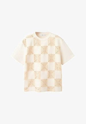 Cămașă crem cu mâneci scurte și guler rotund, având un model în carouri format din pătrate bej croșetate suprapuse pe material.