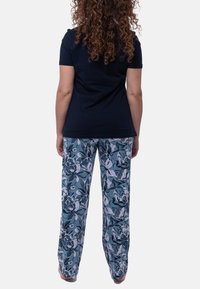 T-paita tummansiniisellä lyhyellä hihalla, yhdistettynä vaaleansinisiin kukkakuosisiiin housuihin, joissa on suuria tummia kukkakuvioita ja rento malli.
