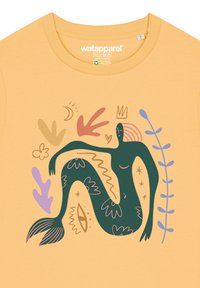 Geel katoenen T-shirt met een groene geïllustreerde figuur met een staart, omringd door kleurrijke abstracte vormen en bladeren.
