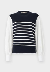 Gilet en tricot bleu marine avec des rayures blanches horizontales, porté sur des manches longues blanches bouffantes et des poignets blancs.