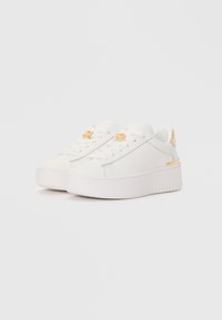 White sneakers with thick soles, leather-like material, round toe, lace-up design, and gold accents on the eyelets and heel.
