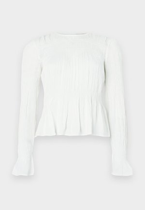 Bluza albă cu mâneci lungi, cu detalii din material adunat, corset cu smocuri și manșete evazate, pe un fundal simplu.