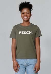 Olijfgroen katoenen t-shirt met opvallende witte tekst "FESCH." op de borst, ronde hals, korte mouwen en een ontspannen pasvorm.