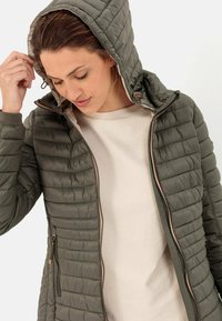 Gequilted olijfgroene hooded jacket met een ritssluiting aan de voorkant, voorzien van zijzakken en een contrasterende binnenvoering. Lichtgewicht, gestructureerd materiaal.