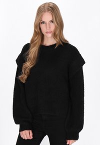 Sort strikket sweater med en afslappet pasform, der har brede ærmer og en cropped kant. Blød tekstur med en let glans i stoffet.