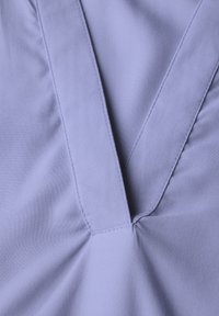 Maglietta lilac a maniche corte con scollo a V, tessuto morbido e cuciture visibili lungo il colletto e l'orlo.