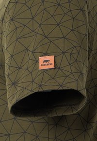Olijfgroene T-shirt met een zwart geometrisch patroon, voorzien van een klein bruin leren Forsberg logo-label aan de onderzoom. Zachte stoftextuur.