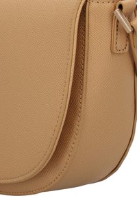 Borsa a tracolla color tan in ecopelle testurizzata, con forma curva, cuciture a contrasto e un piccolo dettaglio in metallo.