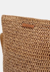 Tkany słomiany torebka w kolorze brązowym z skórzaną metką z napisem "ESPRIT". Faktura jest szorstka, a kształt prostokątny z solidnymi uchwytami.