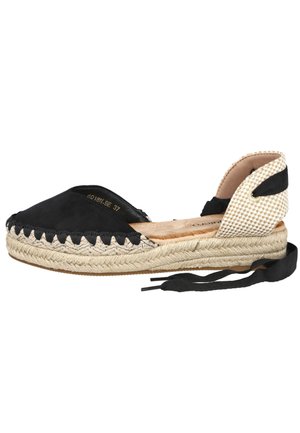 Alpargata plana negra con suela de yute tejido, puntera cerrada, cubierta de talón beige a cuadros y cordones negros para atar al tobillo.