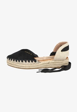 Alpargata plana negra con suela de yute tejido, puntera cerrada, cubierta de talón beige a cuadros y cordones negros para atar al tobillo.