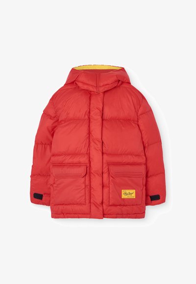 Rdeča puhovka s kapuco, rumenim podlogom, dvema sprednjima žepoma in logotipom. Ima prešito teksturo in črne ježke.