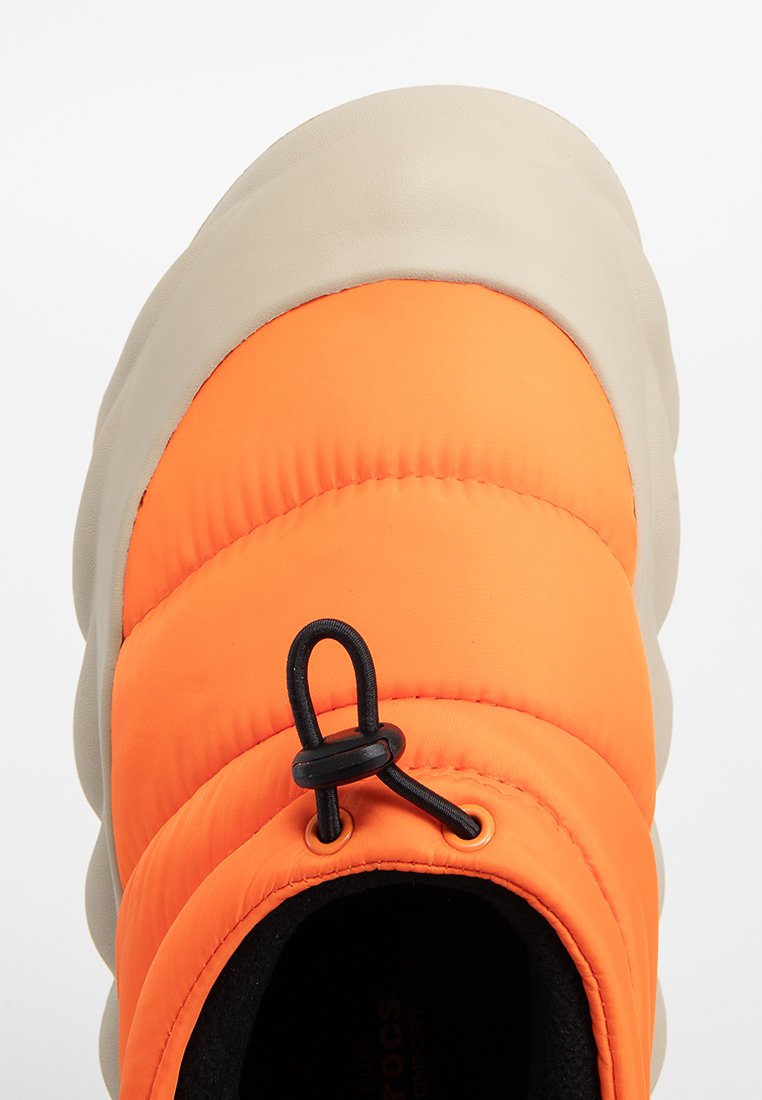 Oranger gepolsterter Oberteil mit einer beigen Gummisohle, ausgestattet mit einem schwarzen Toggle zur Anpassung. Strukturiertes Gewebe und glatte Oberfläche.