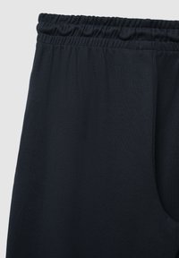 Dunkelblaue Jogginghose mit elastischem Bund, weichem Material und seitlicher Tasche, gestaltet für Komfort und Bewegungsfreiheit.
