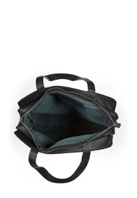 Czarna skórzana torba tote o teksturowanej powierzchni, z zamknięciem na zamek i ciemnozielonym wnętrzem z tkaniny. Posiada dwie solidne rączki.