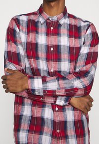 Rood en grijs geruit overhemden met een witte achtergrond, met een klassieke kraag en manchetten, gemaakt van lichte stof.