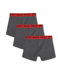 Τρία σκούρα γκρι εσώρουχα boxer με κόκκινες ζώνες μέσης που φέρουν επαναλαμβανόμενα μαύρα λογότυπα "HUGO", εμφανιζόμενα επικαλυπτόμενα σε λευκό φόντο.
