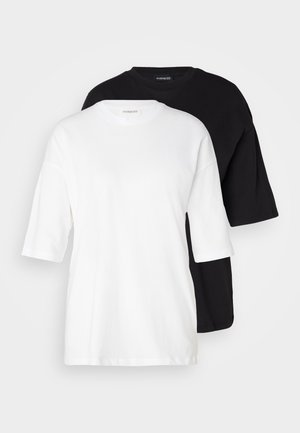 Dve majice s kratkimi rokavi, ena bela in ena črna, narejene iz bombaža. Imajo okrogel izrez in ohlapen, sproščen kroj z gladko teksturo.