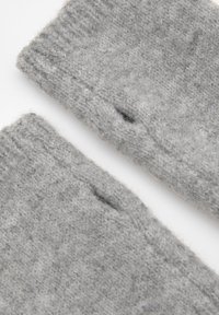 Szürke kötött anyag, puha textúrával és látható varrással. Két darab, az egyik kisebb lyukkal, amely vastagabb széltartóval rendelkezik.