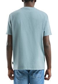 T-shirt en coton bleu clair à manches courtes et ourlet droit, avec un col ras du cou classique et une texture subtile. Vue de dos affichée.