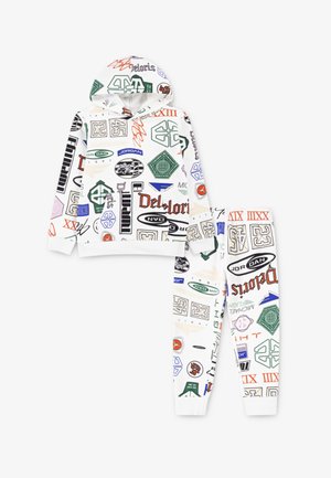 Weißes Hoodie- und Hosen-Set mit verschiedenen bunten Logos und Grafiken in Grün, Rot, Blau und Schwarz, mit gerippten Bündchen an Handgelenken und Knöcheln.