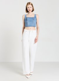 Top corto in denim con scollo quadrato e decorazioni, abbinato a pantaloni bianchi a vita alta e larghi, completato da tacchi bianchi a punta.