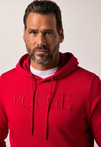 Felpa rossa con "ROUGE" ricamato sul davanti, cappuccio con coulisse, tessuto testurizzato e foderatura interna a contrasto.