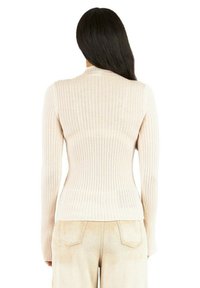 Maglione a coste di un leggero beige, con un design aderente e maniche lunghe, caratterizzato da un collo alto e una texture liscia.