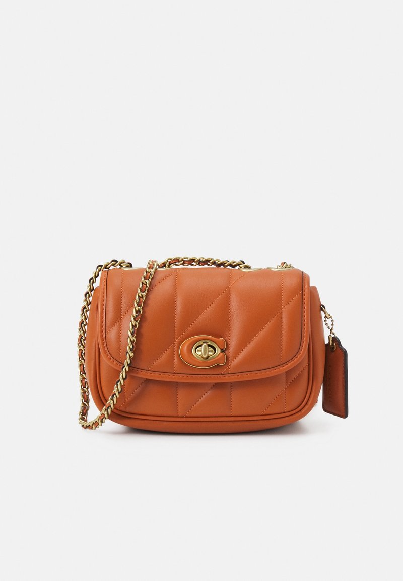 Sac bandoulière en cuir matelassé couleur camel avec bandoulière chaîne dorée et fermoir à tourniquet, avec une petite étiquette assortie sur le côté.