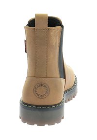 Stivale alla caviglia in pelle tan con lati elastici neri, suola in gomma e logo circolare sul tallone. Presenta accenti cuciti per una maggiore durata.